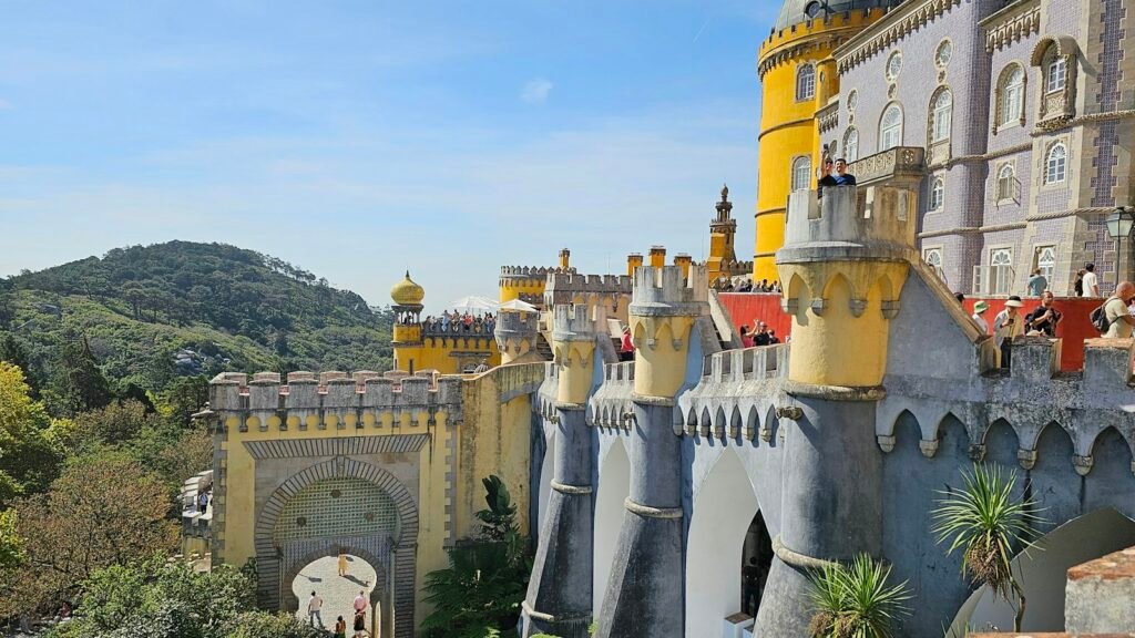 The yellow and red towers of Pena Palace above the forest in Sintra, near Lisbon, Portugal